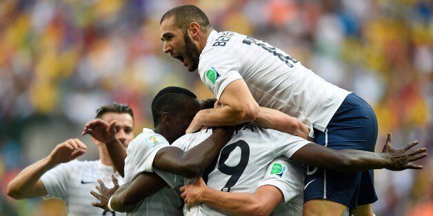 France's midfielder Paul Pogba (C, hidden) celebrates with France's forward Karim Benzema (top) and other teammates after scoring the first goal during a Round of 16 football match between France and Nigeria at Mane Garrincha National Stadium in Brasilia during the 2014 FIFA World Cup on June 30, 2014. AFP PHOTO / FABRICE COFFRINI (Photo credit should read FABRICE COFFRINI/AFP/Getty Images)