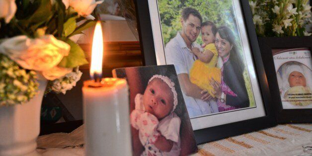 Family pictures are displayed showing Arnold Huizen (L), his wife Yodricunda Theistiasih Titihalawa (R) and their daughter Yelena Clarice Huizen (C), Indonesian victims of Malaysia Airlines MH17 crash in Jimbaran, on Indonesia's resort island of Bali on July 20, 2014. Ukraine and pro-Russian insurgents agreed on July 19 to set up a security zone around the crash site of a Malaysian jet whose downing in the rebel-held east has drawn global condemnation of the Kremlin. Outraged world leaders have demanded Russia's immediate cooperation in a prompt and independent probe into the shooting down on July 17 of flight MH17 with 298 people on board. AFP PHOTO/SONNY TUMBELAKA (Photo credit should read SONNY TUMBELAKA/AFP/Getty Images)