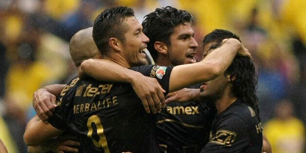 Pumas' Dante Lopez, left, celebrates with his teammates after defeating America at a Mexican soccer league match in Mexico City, Saturday, Aug. 30, 2014. (AP Photo/Christian Palma)