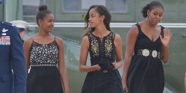 Sasha (L) and Malia (C), the daughters of US President Barack Obama and First Lady Michelle Obama (R), make their way to board Air Force One before departing from Andrews Air Force Base in Maryland on August 30, 2014. Obama is returning to Westchester County, New York to attend the wedding of his personal chef Sam Kass. AFP PHOTO/Mandel NGAN (Photo credit should read MANDEL NGAN/AFP/Getty Images)