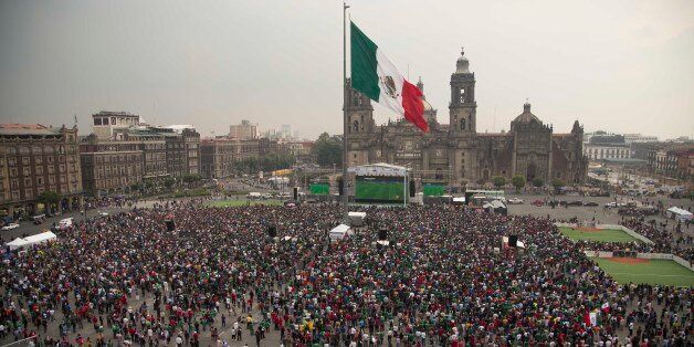 Mexico soccer fans watch their team's 2014 World Cup match with Croatia on giant television screens in Mexico City's main square, the Zocalo, Monday, June 23, 2014. Needing only a tie to advance to the second round of the World Cup for a sixth straight time, Mexico is bound to please its fans. (AP Photo/Moises Castillo)