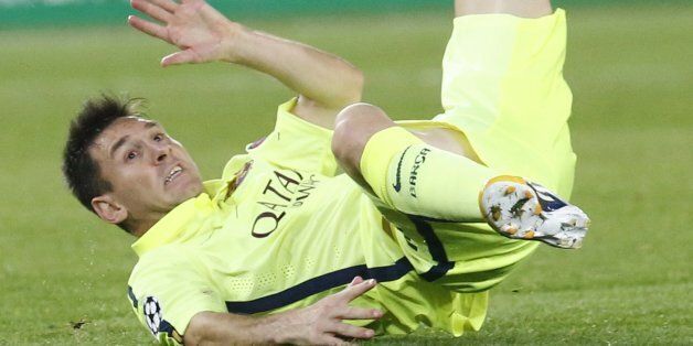 Barcelona's Lionel Messi falls after being tackled during the Champions League Group F soccer match between Paris Saint German and Barcelona at Parc des Princes stadium in Paris, France, Tuesday, Sept. 30, 2014. (AP Photo/Michel Euler)