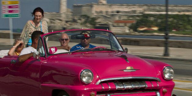 In this Oct. 15, 2014 photo, tourists ride in a classic American car on the Malecon in Havana, Cuba. Those lucky enough to have a pre-revolutionary car can earn money legally by ferrying tourists _ or Cubans celebrating weddings _ along Havanas waterfront Malecon boulevard. (AP Photo/Franklin Reyes)