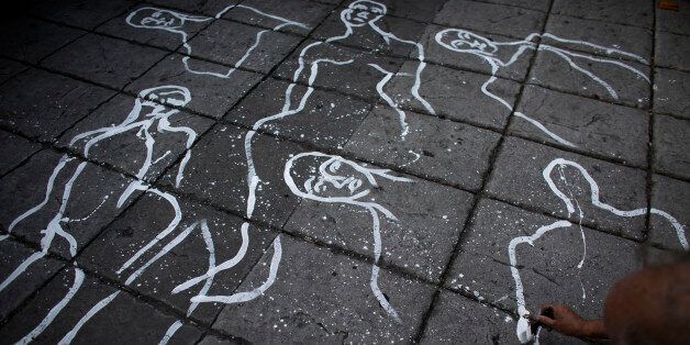 Artist Gabriel Macotela paints figures representing Mexico's many dead, on the surface of a main boulevard as thousands marched through the capital to demand that the government find the 43 students who disappeared in southern Guerrero State, in Mexico City, Wednesday, Oct. 8, 2014. Investigators still had no word on whether the 28 bodies found in a mass grave over the weekend included any of the missing students, who disappeared after two attacks allegedly involving Iguala police in which six people were killed and at least 25 wounded. (AP Photo/Rebecca Blackwell)