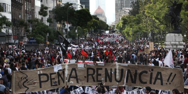 Demonstrators march in protest of the disappearance of 43 students in the state of Guerrero, in Mexico City, Wednesday, Oct. 8, 2014. The demonstrators carry a banner that reads in Spanish "Pena Quit!" demanding that President Enrique Pena Nieto quit the presidency. Federal officials say they still have no explanation for the Sept. 26 violence that killed six, wounded at least 25 and left so many missing. Investigators still have no word on whether the 28 bodies found in a mass grave last weekend in the state of Guerrero included some of the missing students. (AP Photo/Marco Ugarte)