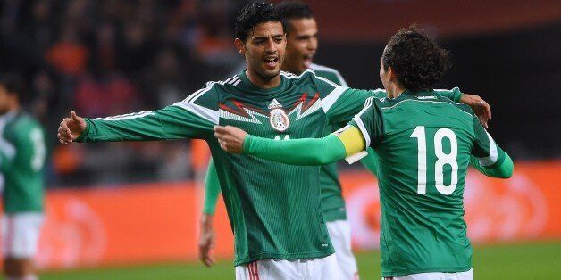 Mexico's forward Carlos Vela (L) celebrates with Mexico's defender Andres Guardado after scoring the first goal during the friendly football match betwenn the Netherlands and Mexico in Amsterdam November 12, 2014. AFP PHOTO / EMMANUEL DUNAND (Photo credit should read EMMANUEL DUNAND/AFP/Getty Images)