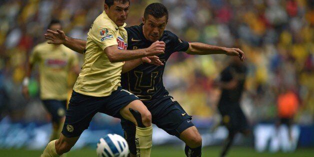 America's Pablo Aguilar (L) disputes the ball with Pumas' Dante Lopez (R) during their Mexican Apertura tournament football match at the Azteca stadium in Mexico City on August 30, 2014. AFP PHOTO/ Yuri CORTEZ (Photo credit should read YURI CORTEZ/AFP/Getty Images)