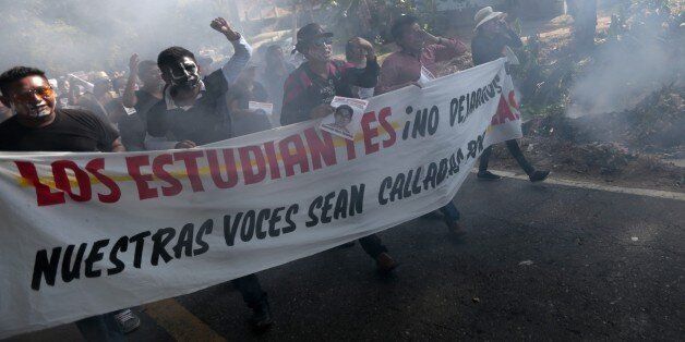 People shout slogans during a protest march at Tecoanapa, in Guerrero State, Mexico, on December 11, 2014. People protested over the disappearance of 43 college students, of which Alexander Mora was recently identified following the finding of remains in a landfill in Cocula. AFP PHOTO/PEDRO PARDO (Photo credit should read Pedro PARDO/AFP/Getty Images)