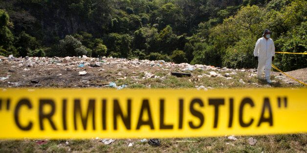 A forensic examiner walks along a garbage-strewn hillside above a ravine where examiners are searching for human remains in densely forested mountains outside Cocula, Guerrero state, Mexico, Tuesday, Oct. 28, 2014. Suspects arrested this week told prosecutors that many of the 43 students who disappeared Sept. 26 from the town of Iguala had been held near this location. (AP Photo/Rebecca Blackwell, Pool)
