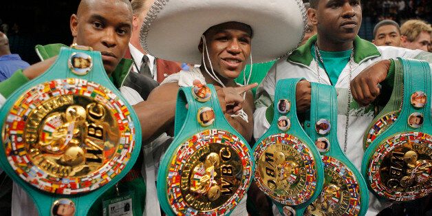 Floyd Mayweather Jr., center, poses with his title belts after defeating Oscar De La Hoya in a split decision following their WBC super welterweight world championship boxing match on Saturday, May 5, 2007, at the MGM Grand Garden Arena in Las Vegas. (AP Photo/Jae C. Hong)