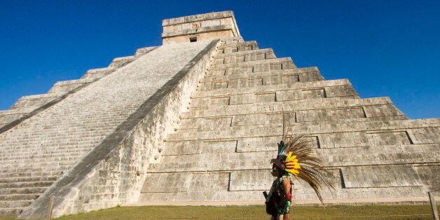 A Mexican man wearing a pre-hispanic costume walk next to the kukulkan pyramid at the Chichen Itza archaeological park, in Yucatan state, Mexico on December 20, 2012. Mexico is one of five countries preparing to celebrate on December 21, the end of the Maya Long Count Calendar --Baktun 13-- which began in 3114 BC. AFP PHOTO/Pedro Pardo (Photo credit should read Pedro PARDO/AFP/Getty Images)