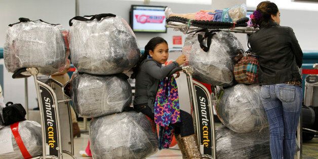 Liedy Hernandez of Miami waits in line with luggage at Miami International Airport before traveling to Cuba with her family, Monday, Dec. 19, 2011, in Miami. As the holidays approach this year, thousands of Cuban-Americans are taking advantage of the Obama administration's relaxed travel regulations to return to the island. (AP Photo/Lynne Sladky)