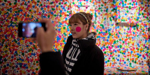 A tourist is photographed while visiting the exhibition "Infinite Obsession" of famed Japanese artist Yayoi Kusama at the Malba Art Museum in Buenos Aires, Argentina, Monday, July 15, 2013. Kusama's exhibition, that will be open until mid-September, includes paintings, works on paper, sculptures, videos, slide shows and installations created between 1950 and 2013. (AP Photo/Natacha Pisarenko)
