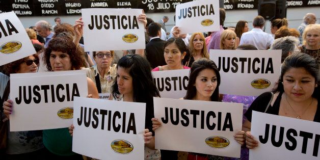 People gather outside the AMIA Jewish community center asking for "Justice" in the death of a prosecutor who had accused Argentinas president of a criminal conspiracy, in Buenos Aires, Argentina, Wednesday, Jan. 21, 2015. Special prosecutor Alberto Nisman, who had been investigating the 1994 bombing of the Jewish community center that killed 85 people and who accused President Cristina Fernandez of shielding Iranian suspects, was found dead from a gunshot to the head, in his apartment late Sunday, hours before he was to testify in a Congressional hearing about the case. (AP Photo/Rodrigo Abd)