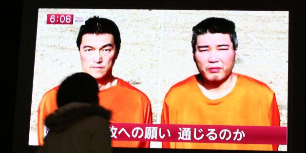 A passer-by watches a TV news program reporting two Japanese hostages, Kenji Goto, left, and Haruna Yukawa, held by the Islamic State group, in Tokyo, Friday, Jan. 23, 2015. Militants affiliated with the Islamic State group have posted an online warning that the "countdown has begun" for the group to kill a pair of Japanese hostages. (AP Photo/Eugene Hoshiko)
