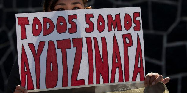 A protestor holds a sign reading in Spanish "We are all Ayotzinapa," referring to the disappearance of 43 college students last year, during a demonstration outside the headquarters of Mexico's presidential guard, in Mexico City, Monday, Jan. 12, 2015. The protestors refused to leave until an officer accepted their letter requesting that a civilian commission be allowed inside to inspect the base for evidence of the students, who disappeared last September in the southern state of Guerrero. (AP Photo/Rebecca Blackwell)