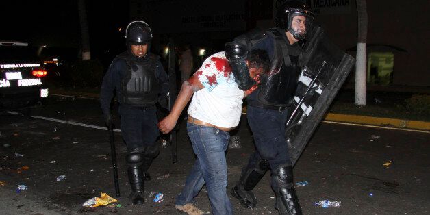An injured protester is taken into custody by police during a protest demanding better labor conditions for teachers in Acapulco, Mexico, late Tuesday, Feb. 24, 2015. Police clashed with union members representing teachers and other public workers who were blocking the airport. Demonstrators also protested the Sept. 26, 2014 disappearance of 43 students in Guerrero state. (AP Photo/Bernandino Hernandez)