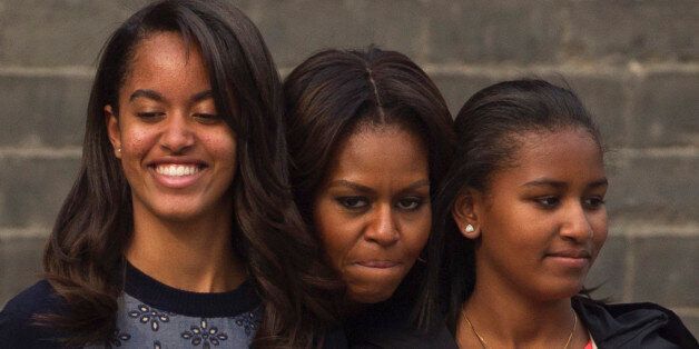 U.S. first lady Michelle Obama, center, hugs her daughters Malia, left, and Sasha, right, when they watch a performance during their visit to an ancient city wall in Xi'an, in northwestern China's Shaanxi province, Monday, March 24, 2014. (AP Photo/Alexander F. Yuan)