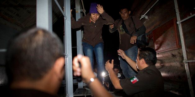 Immigration officials remove Central American migrants from a northbound freight train during a raid by federal police in San Ramon, Mexico, just after midnight on the morning of Friday, Aug. 29, 2014. The largest crackdown by Mexican authorities on illegal migration in decades has decreased the flow of Central American migrants trying to reach the United States, and has dramatically cut the number of child migrants and families, according to officials and eyewitness accounts along the perilous route.(AP Photo/Rebecca Blackwell)