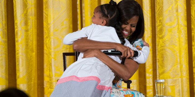 Anaya Brodie, left, hugs first lady Michelle Obama during the White Houseâs annual "Take Our Daughters and Sons to Work Day" in the East Room on Wednesday, April 22, 2015, in Washington. Obama took questions from children of Executive Office employees, and local young people from the Boys and Girls Club and D.C. Child and Family Services. (AP Photo/Evan Vucci)