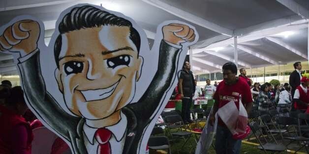 A supporter carries a caricature of Mexican presidential candidate for the Institutional Revolutionary Party (PRI), Enrique PeÃ±a Nieto, at the end of the celebrations held at the party's headqurters in Mexico City after the first official results of the presidential election were announced, on July 1, 2012. Enrique PeÃ±a Nieto, the new face of the party that governed Mexico for seven decades, won Sunday's presidential election, according to first official results by the independent Federal Electoral Institute (IFE). PeÃ±a Nieto had around 38 percent of the vote against around 31 percent for his nearest rival, leftist Andres Manuel Lopez Obrador from the Party of the Democratic Revolution (PRD), according to the early count. AFP PHOTO/OMAR TORRES (Photo credit should read OMAR TORRES/AFP/GettyImages)