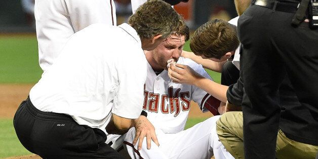 PHOENIX, AZ - APRIL 28: Archie Bradley #25 of the Arizona Diamondbacks is tended to on the pitcher's mound after getting hit in the face with a line drive against the Colorado Rockies at Chase Field on April 28, 2015 in Phoenix, Arizona. (Photo by Norm Hall/Getty Images)