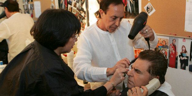 ** ADVANCE FOR WEEKEND, OCT. 7-8 ** Mario Kreutzberger, right, talks on the phone while having his hair and make-up done by Maria Lok, left, and Antoine Mari, center, before taping the television show "Sabado Gigante" in Miami on Thursday, Sept. 21, 2006. Kreutzberger is the show's host, Don Francisco. (AP Photo/Lynne Sladky)