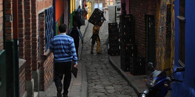 Men go about their business in a narrow street in the historic neighborhood of La Candelaria in Bogota on September 17, 2009. La Candelaria is Bogota's oldest neighbourhood and the city's historical center, known for its colonial houses with wooden balconies and clay shingle roofs. AFP PHOTO/Eitan Abramovich -------------- MORE PHOTOS IN IMAGE FORUM -------------- (Photo credit should read EITAN ABRAMOVICH/AFP/Getty Images)