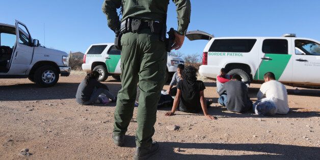 WALKER CANYON, AZ - MARCH 06: A U.S. Border Patrol agent guards a group of Mexican immigrants caught after they crossed into the United States on March 6, 2013 near Walker Canyon, Arizona. Due to broad federal sequestration budget cuts, Border Patrol agents are expected to begin taking unpaid furlough days in April, as Customs and Border Protection funding is expected to be reduced by more than $500 million. (Photo by John Moore/Getty Images)