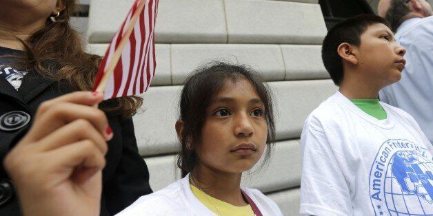 Ebenyn Roca, 9, of Miami, holds an American flag participates in a rally led by the New Orleans Worker Center for Racial Justice and the Congress of Day Laborers, outside the U.S. Fifth Circuit Court of Appeals in New Orleans, Friday, April 17, 2015. A three-judge panel began hearing arguments whether to lift a temporary hold imposed by a federal judge in Texas on President Barack Obama's executive action seeking to shield millions of immigrants from deportation. (AP Photo/Gerald Herbert)