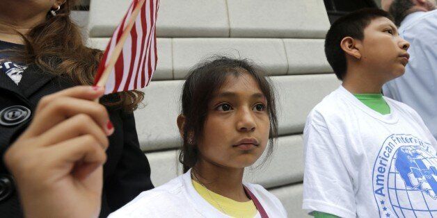 Ebenyn Roca, 9, of Miami, holds an American flag participates in a rally led by the New Orleans Worker Center for Racial Justice and the Congress of Day Laborers, outside the U.S. Fifth Circuit Court of Appeals in New Orleans, Friday, April 17, 2015. A three-judge panel began hearing arguments whether to lift a temporary hold imposed by a federal judge in Texas on President Barack Obama's executive action seeking to shield millions of immigrants from deportation. (AP Photo/Gerald Herbert)