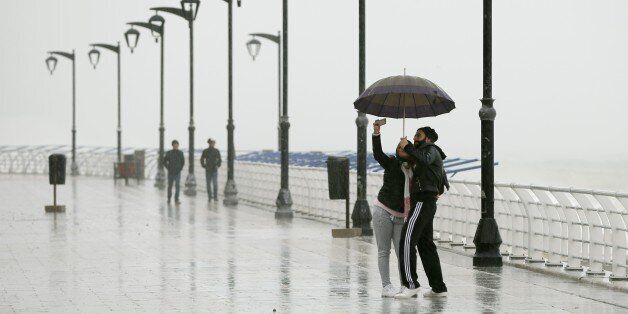 A Lebanese couple takes a selfie under the rain as they walk at Beirut's seaside corniche in Ain al-Mreisseh during a heavy storm on February 11, 2015. A fierce sandstorm lashed Egypt, Israel and Lebanon closing the Suez Canal to ships and grounding domestic flights in Israel. AFP PHOTO/JOSEPH EID (Photo credit should read JOSEPH EID/AFP/Getty Images)
