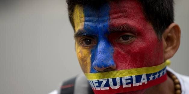 A man wears a narrow strip in the colors of Venezuela's flag over his mouth in protest of officials breaking up camps maintained by student protesters, in Caracas, Venezuela, Thursday, May 8, 2014. Hundreds of security forces broke up four camps maintained by student protesters, arresting more than 200 people in a pre-dawn raid. The camps of small tents were installed more than a month ago in front of the UN building and other anti-government strongholds in the capital to protest against President Nicolas Maduro's government. (AP Photo/Fernando Llano)