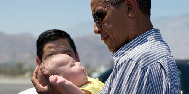 President Barack Obama holds one of the twin daughters of Rep. Raul Ruiz, D-Calif., background, as he arrives on Air Force One at Palm Springs International airport in Palm Springs, Calif, Saturday, June 20, 2015. The president will be golfing in the area this weekend. (AP Photo/Carolyn Kaster)