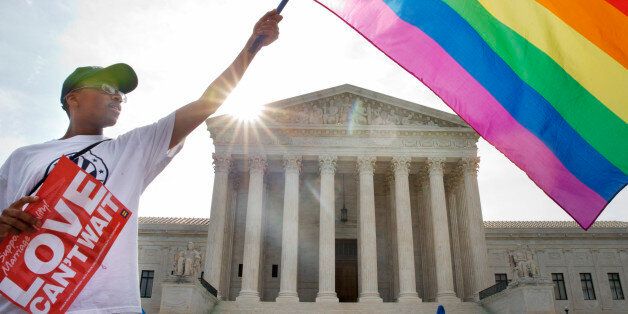 Carlos McKnight of Washington, waves a flag in support of gay marriage outside of the Supreme Court in Washington, Friday June 26, 2015. A major opinion on gay marriage is among the remaining to be released before the term ends at the end of June. (AP Photo/Jacquelyn Martin)