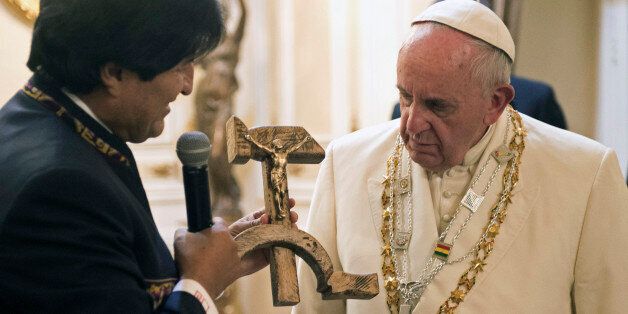 Pope Francis is presented with a gift of a crucifix carved into a wooden hammer and sickle, the Communist symbol uniting labor and peasants, by Bolivian President Evo Morales in La Paz, Bolivia, Wednesday, July 8, 2015. Apart from the carved hammer and sickle, Morales gave Francis another politically loaded gift, a copy of "The Book of the Sea," which is about the loss of Bolivia's access to the sea during the War of the Pacific with Chile in 1879-83. Morales said things have changed with this pope and the Bolivian people are greeting Francis as someone who is "helping in the liberation of our people." (L'Osservatore Romano/Pool Photo via AP)