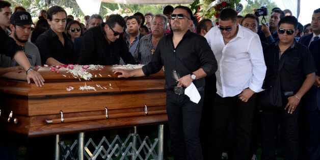 Friends and relatives of Mexican ballad singer Joan Sebastian gather around his coffin at the cemetery in Juliantla, Mexico, Friday, July 17, 2015. Sebastian, one of Mexico's great ballad singers, died on July 13. He was 64. After five days of homage and farewells by thousands of fans, Sebastian was laid to rest in his hometown's cemetery. (AP Photo/Tony Rivera)