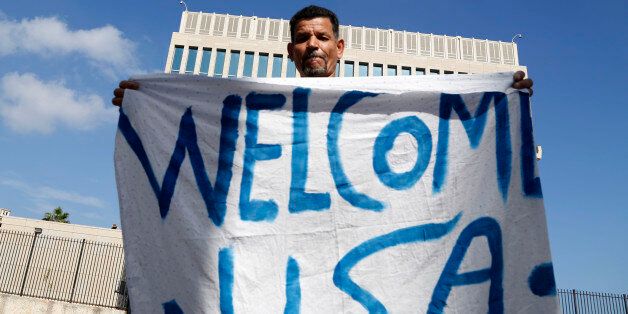 Cuban Lazaro Cudilleiro holds a banner in front of the United States Embassy in Havana, Cuba, Monday, July 20, 2015. A new era began in Cuba and U.S. relations with little fanfare when an agreement between the two nations to resume normal ties on July 20 came into force just after midnight Sunday and the diplomatic missions of each country were upgraded from interests sections to embassies. (AP Photo/Desmond Boylan)