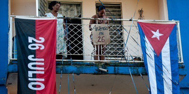 Women stand on a balcony with flags and banners to commemorate the 1953 Moncada Barracks assault, in Artemisa, 50 km southwest of Havana, on July 24, 2014. Cuba will celebrate in Artemisa on July 26, the 61th anniversary of ex-leader Fidel Castro's Moncada Barracks assault -- widely seen as the start to the country's communist revolution. The events, led by current President Raul Castro, kicked off in the courtyard of the former Moncada Garrison, where in 1953, a young Fidel and more than 100 rebels attempted to overthrow dictator Fulgencio Batista. AFP PHOTO / YAMIL LAGE (Photo credit should read YAMIL LAGE/AFP/Getty Images)