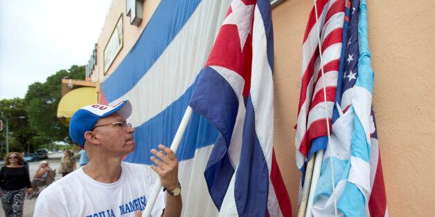 Osvaldo Hernandez unfurls a Cuban flag as he and others protest against the opening of the U.S. embassy in Havana, during a demonstration in the Little Havana neighborhood, Friday, Aug. 14, 2015, in Miami. (AP Photo/Wilfredo Lee)
