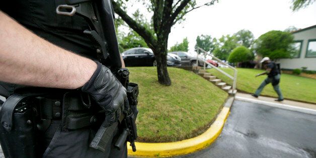 A Little Rock police officer, left, holds his weapon as a Drug Enforcement Administration officer, right, patrols outside of a medical clinic in Little Rock, Ark., Wednesday, May 20, 2015. Federal agents raided medical clinics, pharmacies and other locations across the South on Wednesday, wrapping up what a federal official called a long-running crackdown on prescription drug abuse. (AP Photo/Danny Johnston)