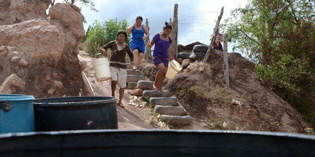 Women head to collect water after a tanker filled containers in a poor neighbourhood on the outskirts of Tegucigalpa on August 7, 2014. Honduras and the rest of Central America has been hit by a major drought that has killed thousands of cattle, dried up crops and forced cities to ration electricity. Honduras, Costa Rica and Guatemala have declared emergencies in the worst affected areas to speed up aid delivery. The lack of rain has been blamed on the probable arrival of the El Nino weather phenomenon, which is characterized by unusually warm Pacific ocean temperatures that can trigger droughts. AFP PHOTO/Orlando SIERRA (Photo credit should read ORLANDO SIERRA/AFP/Getty Images)