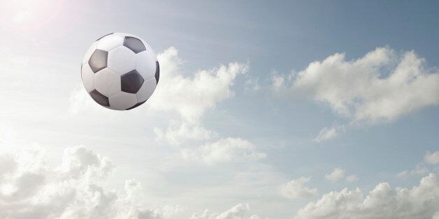 Soccer ball flying in cloudy sky
