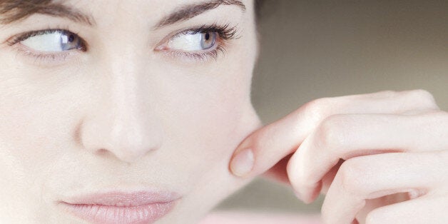 Beauty portrait of a mature woman pulling on the skin of her face.