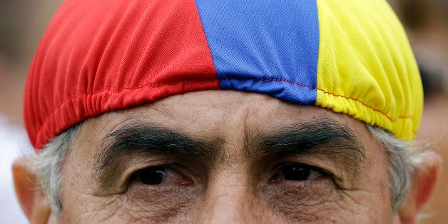 A man wearing a head covering, representing the colors of Colombia's national flag, takes part in a demonstration outside the Venezuelan consulate to protest Venezuela's border crackdown, in Bogota, Colombia, Wednesday, Aug. 26, 2015. The two nations' foreign ministers met in Colombia Wednesday, to try to cool tensions roused when Venezuelan President Nicolas Maduro closed a major border crossing, declared a state of emergency in six western cities and deported more than 1,000 Colombian migrants. (AP Photo/Fernando Vergara)