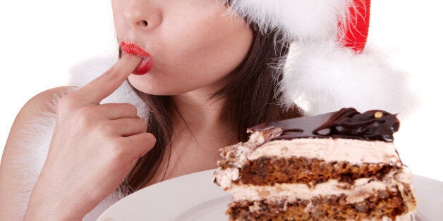 Christmas girl in santa hat and cake on plate.