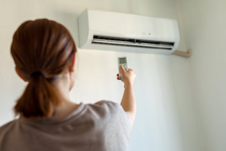 Woman turning on air conditioner with remote