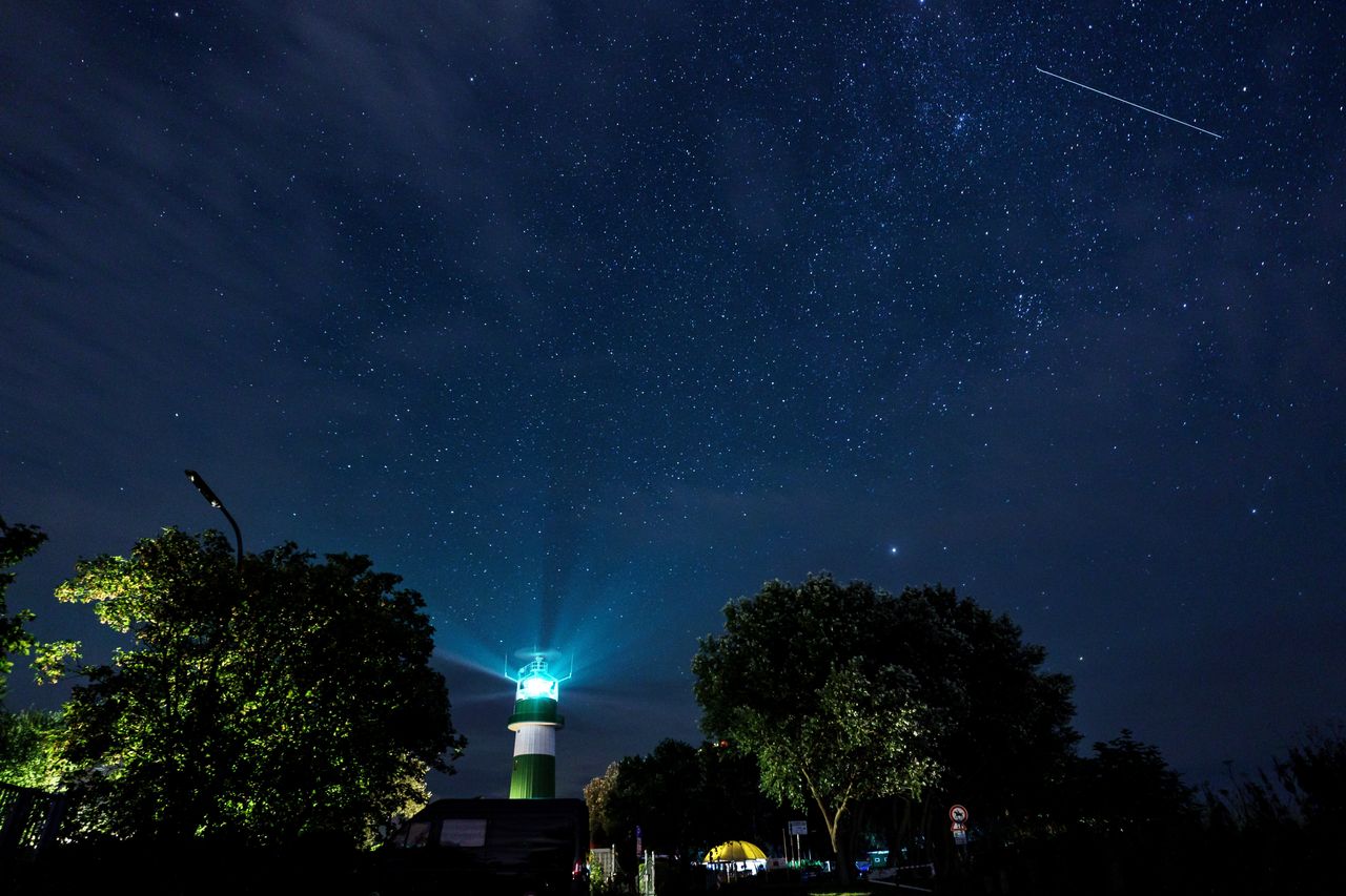 A shooting star passes over the Bülk lighthouse on the shore of the Baltic Sea