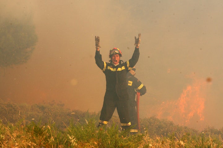 A firefighter yells while battling a forest fire in Greece.