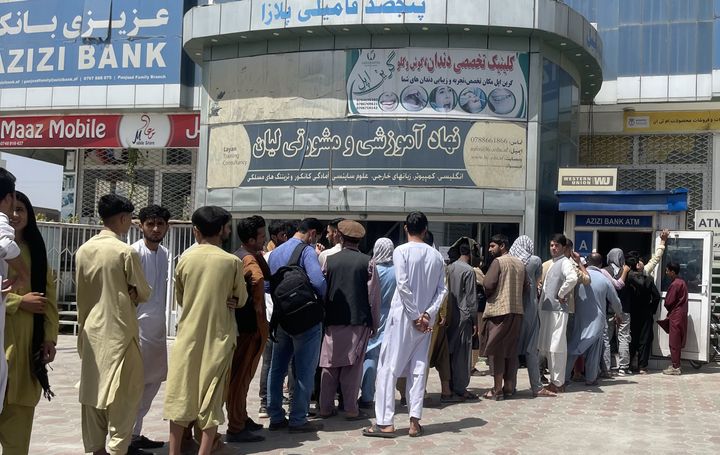 Afghan people line up outside AZIZI Bank to take out cash as the bank suffers amid money crises in Kabul, Afghanistan, on Sunday. 